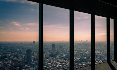 摄影师手持全景相机在城市天台拍摄360度城市全景，背景是广阔城市轮廓与晴朗蓝天